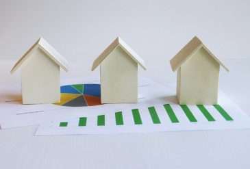 Model homes positioned over real estate data charts